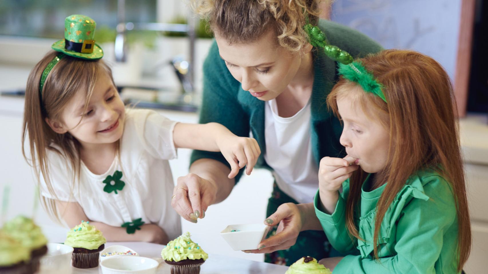 Una mujer celebra San Patricio cocinando recetas típicas con dos niñas. iStock.