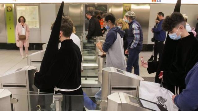 Un par de jóvenes vestidos de nazarenos, en el Metro de Málaga.