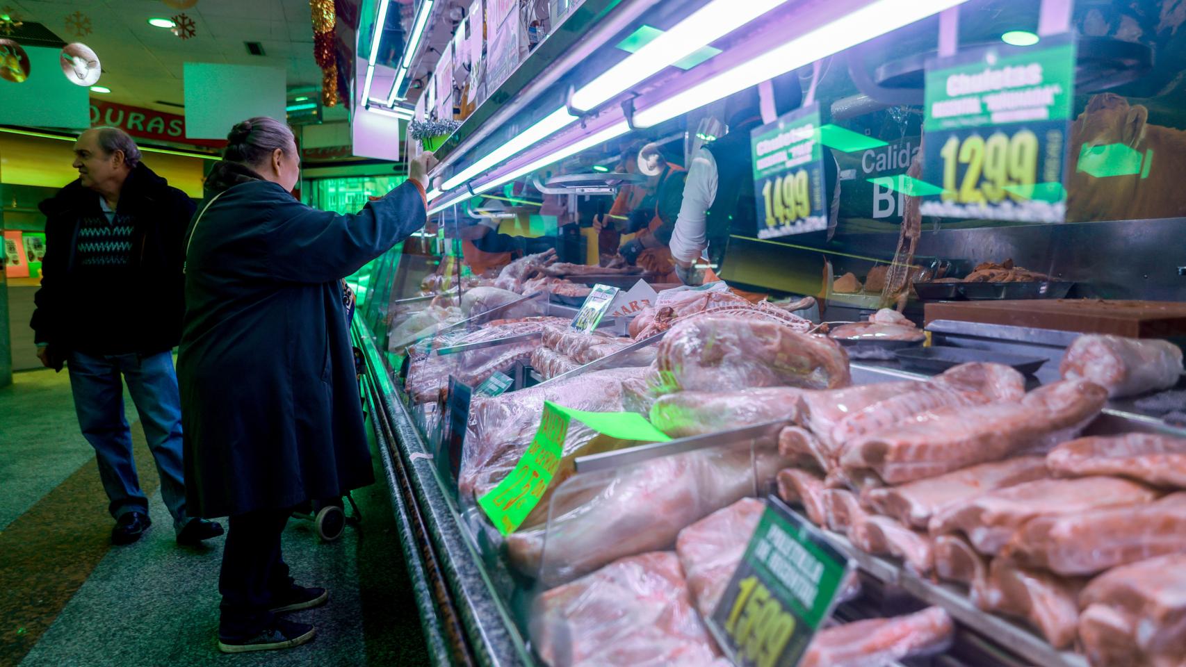 Varias personas comprando en una carnicería.