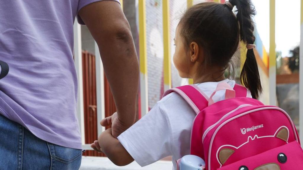Un padre lleva a su hija al colegio en el primer día de curso.