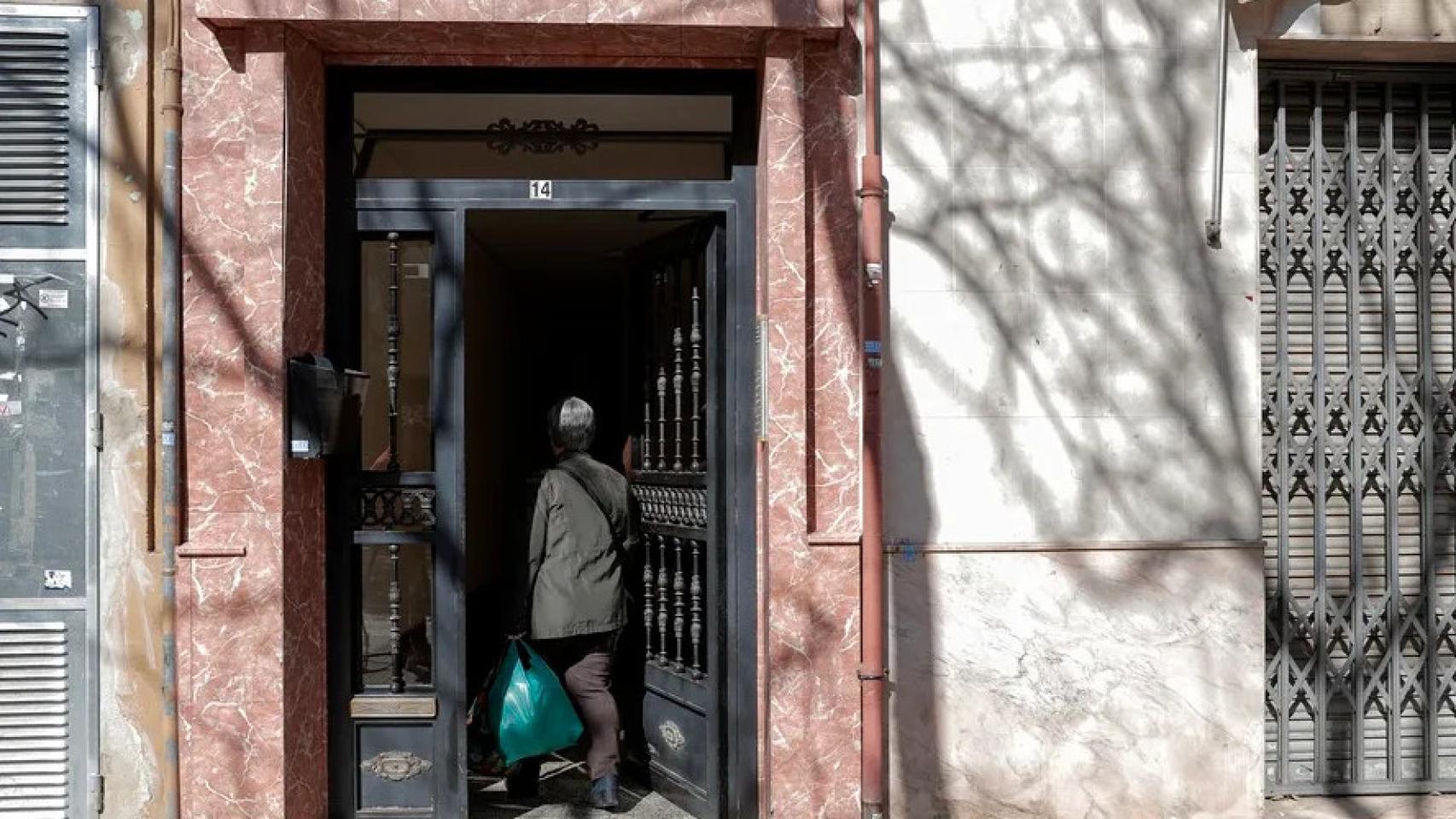 Una persona entra en el portal del edificio.