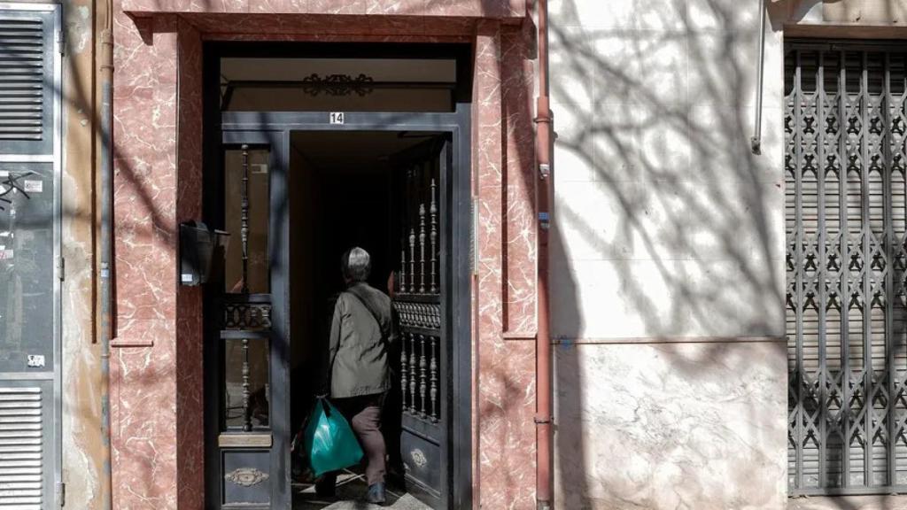 Una persona entra en el portal del edificio.
