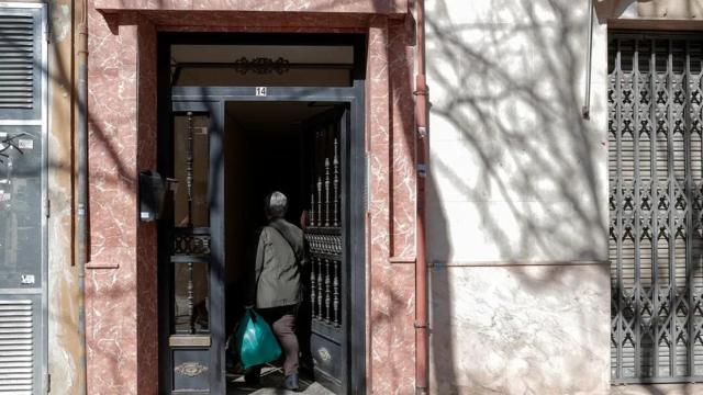 Una persona entra en el portal del edificio.