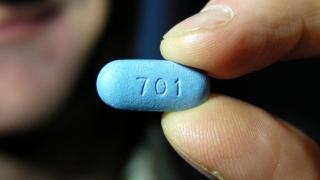Un hombre sostiene una pastilla de la PrEP.