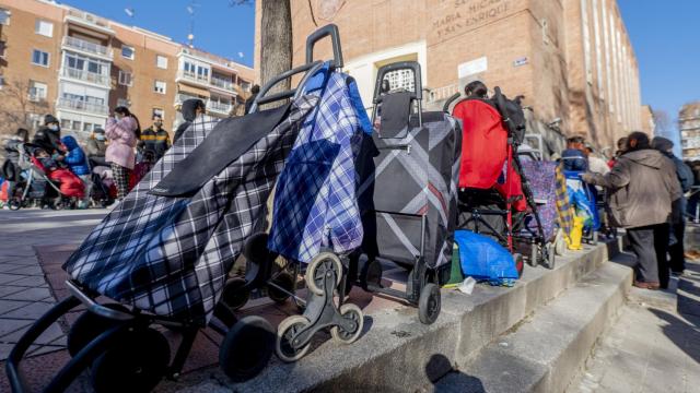 Varias personas hacen cola para recibir alimentos de la Fundación Madrina, en la plaza de San Amaro, en Madrid, en una imagen de archivo.