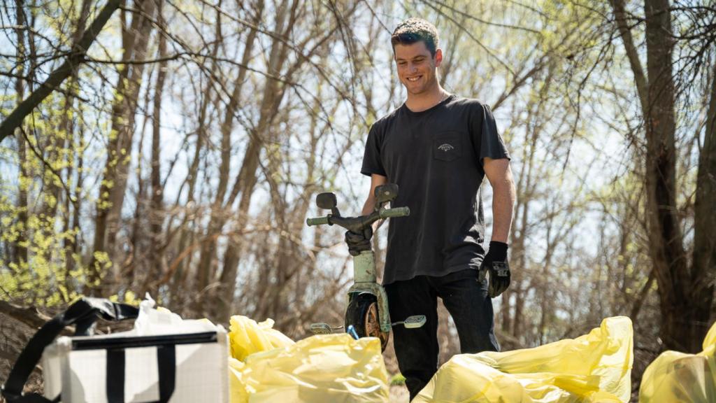 El actor Miguel Bernardeau sujeta el triciclo que ha encontrado en el cauce del río Jarama.