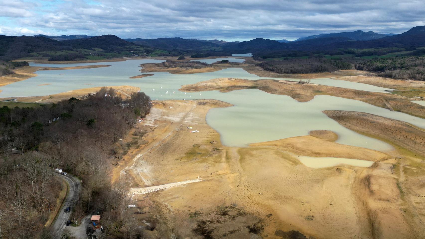 El lago Montbel parcialmente seco al pie de las montañas de los Pirineos, en marzo de 2023.