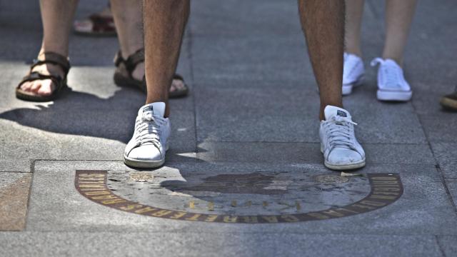 Unos viandantes se paran en la antigua placa del Kilómetro Cero en  la Puerta del Sol.