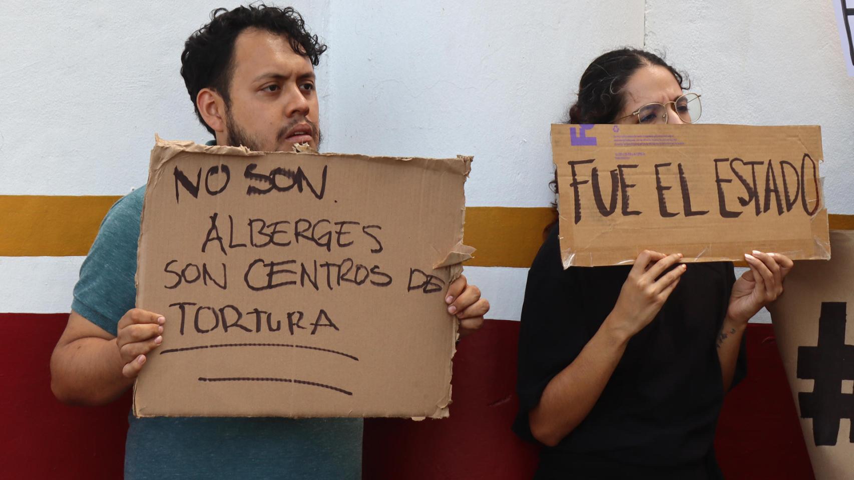 Dos migrantes protestan en frontera sur de México tras fuego en centro migratorio.