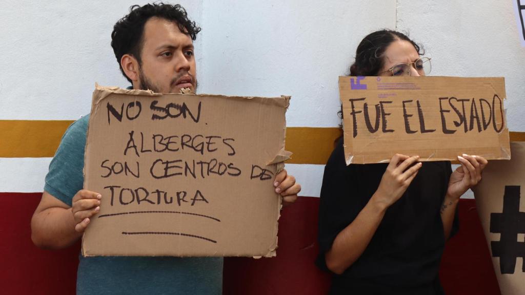 Dos migrantes protestan en frontera sur de México tras fuego en centro migratorio.