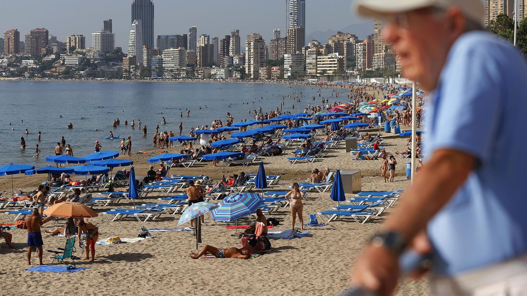 Turistas en la playa de Benidorm, con el 'skyline' de la ciudad al fondo.