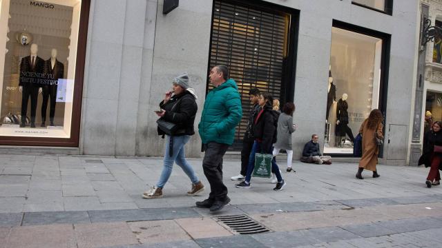Varias personas en una calle comercial frente a la remodelada y peatonalizada Puerta del Sol, a 4 de diciembre de 2022.
