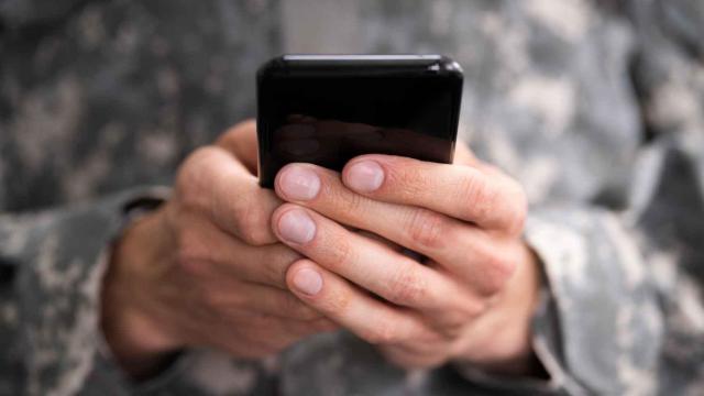 Un joven sostiene un teléfono móvil entre manos.
