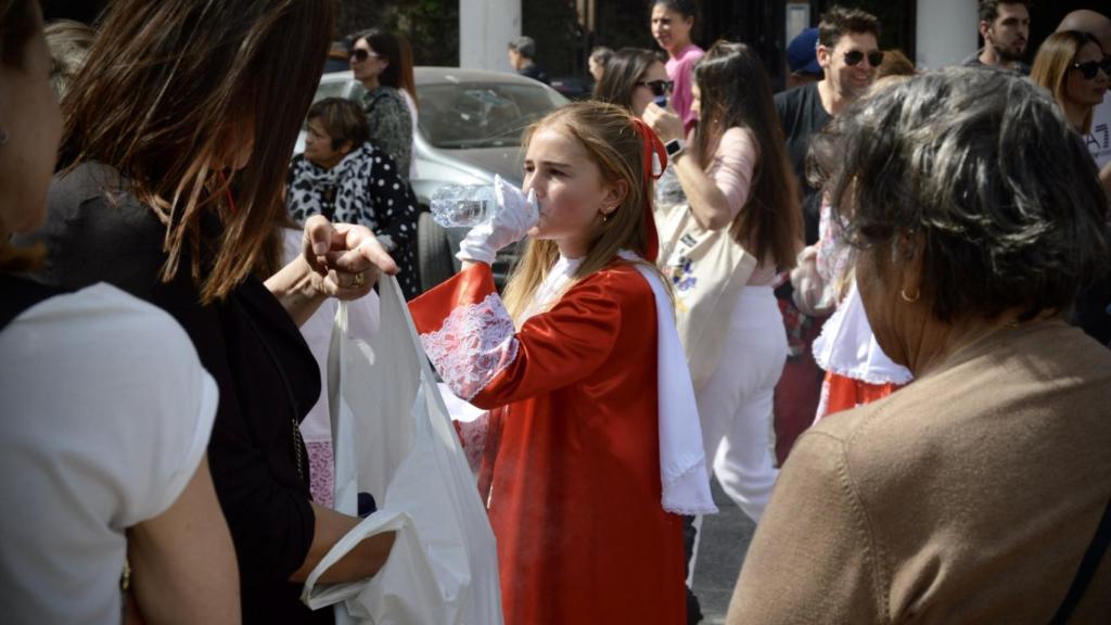 Una monaguilla de la procesión bebiendo agua.