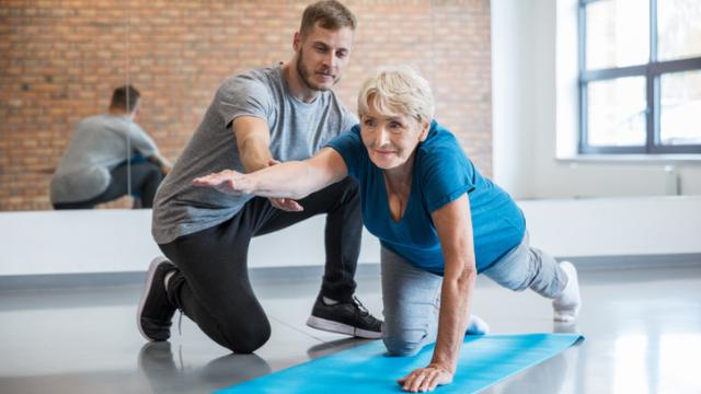 Un monitor deportivo dirige los ejercicios de una paciente.