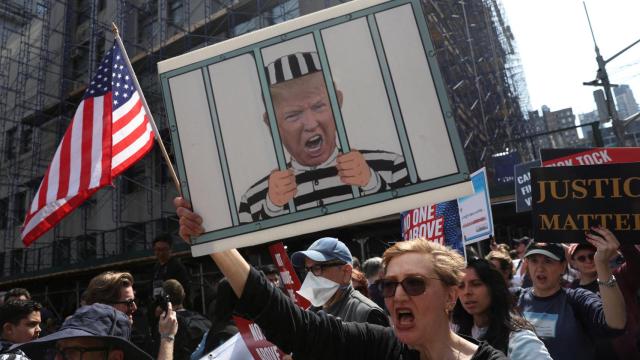 Un grupo de personas se manifiesta frente al Tribunal Penal de Manhattan antes de la lectura de cargos a Donald Trump.