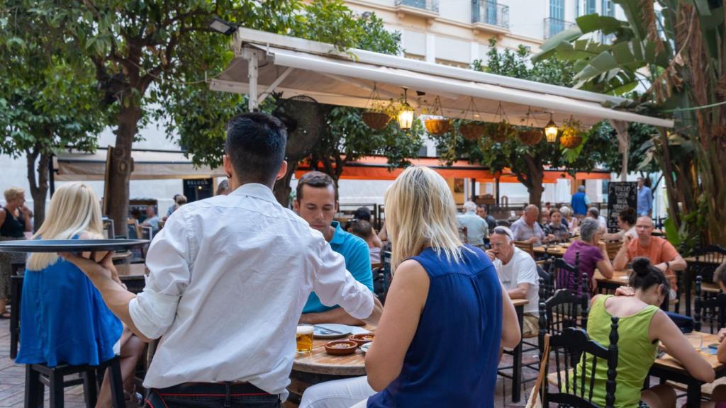 Un camarero atendiendo a unos clientes en Málaga.