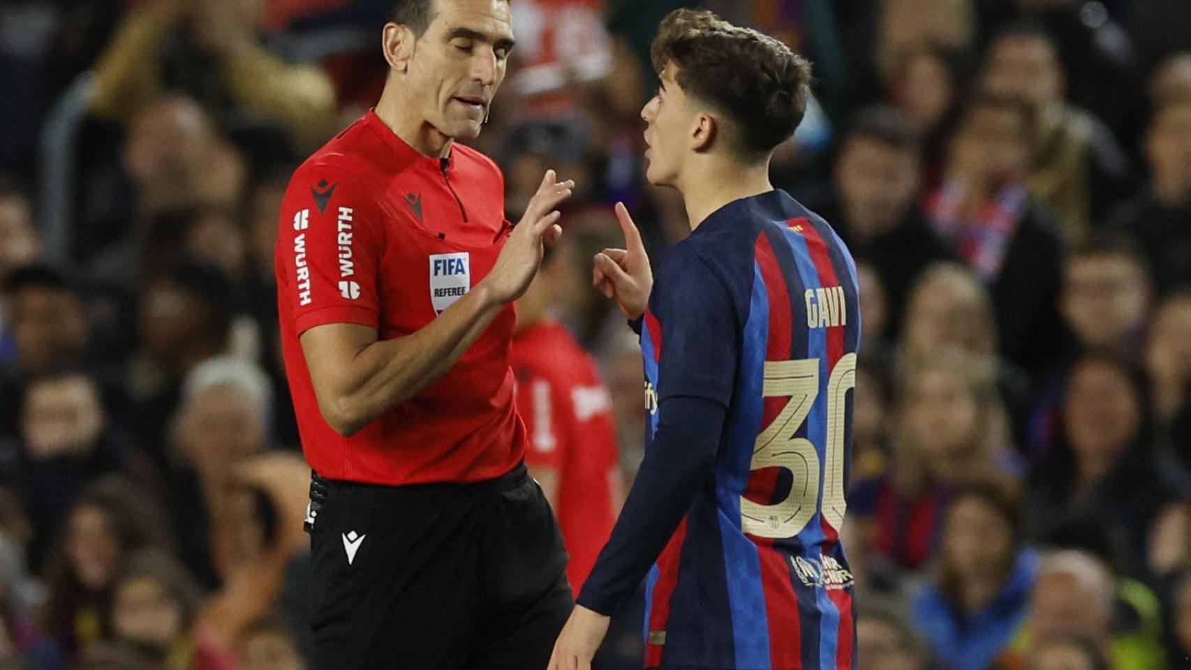 Gavi discute con Martínez Munuera una acción sobre el terreno de juego.