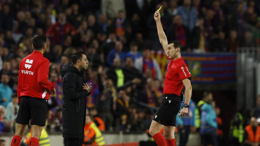 Xavi Hernández recibe la tarjeta amarilla de Martínez Munuera por protestar.