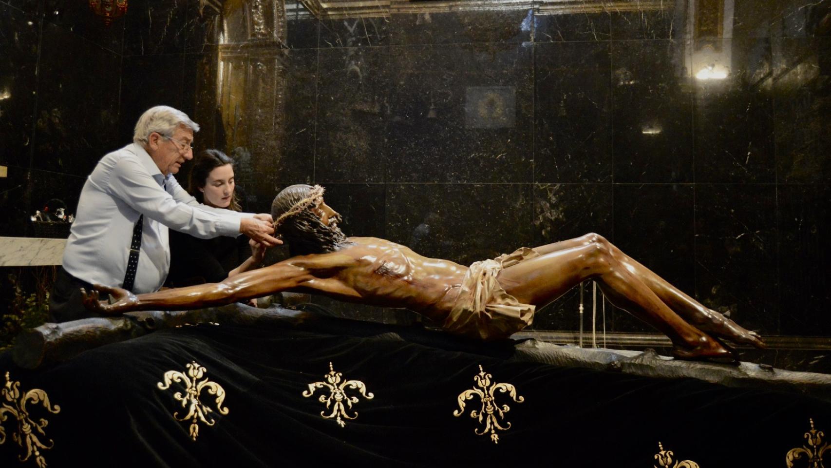 Ramón y Marta prueban la corona de espinas al Cristo de la Buena Muerte.