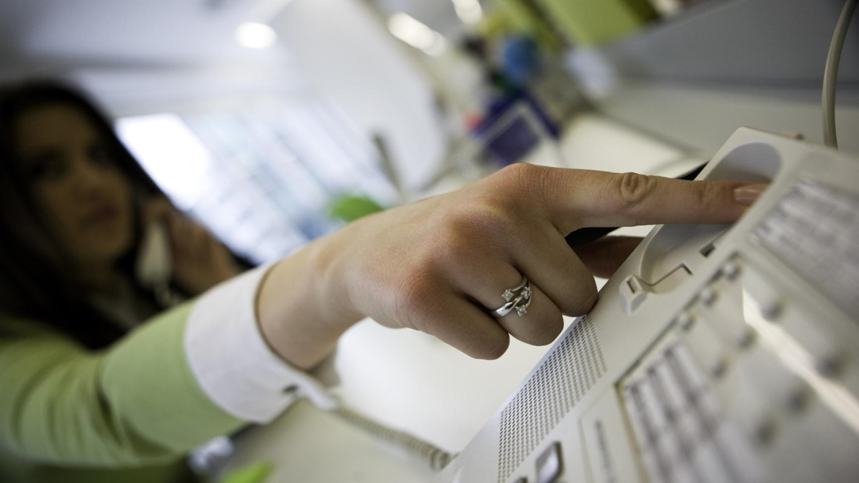 Imagen de archivo de una mujer colgando el teléfono fijo. iStock