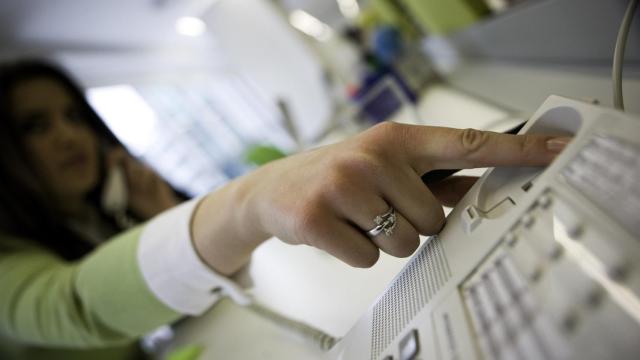 Imagen de archivo de una mujer colgando el teléfono fijo.