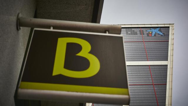 Un cartel con el símbolo de Bankia delante del logo de Caixabank tras su sustitución por el de Bankia en las torres Kio, en Madrid (España), en 2021.