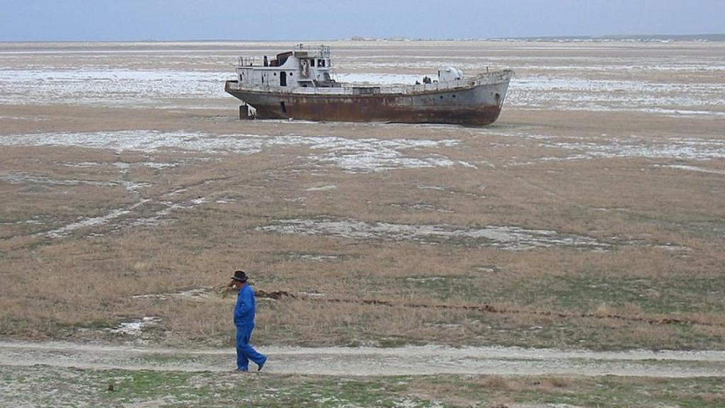 Una persona pasa junto a un barco encallado en el mar de Aral.