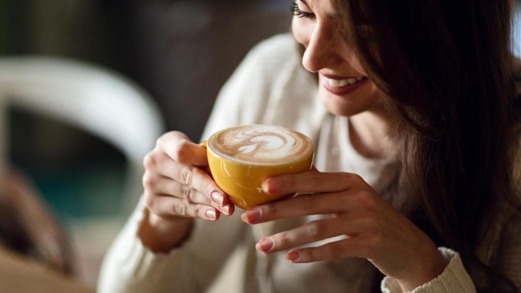 Mujer disfrutando en taza de café recién hecho.