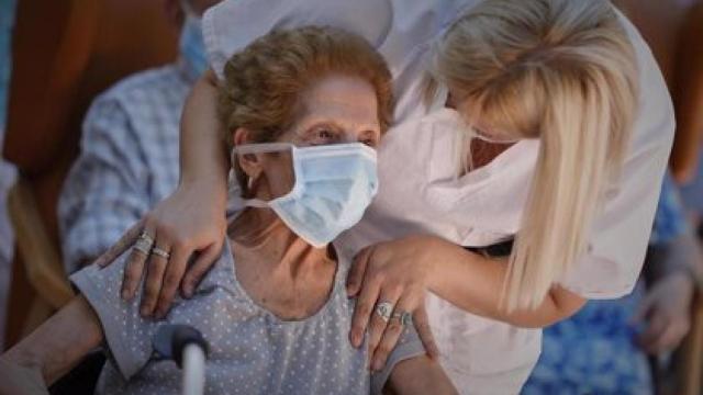 Una residente de una residencia de ancianos de Madrid y una sanitaria con mascarilla.