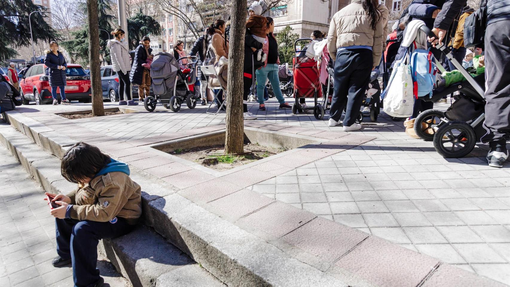 Un grupo de personas espera una cola durante la entrega de ropa de abrigo y zapatos nuevos a niños vulnerables.