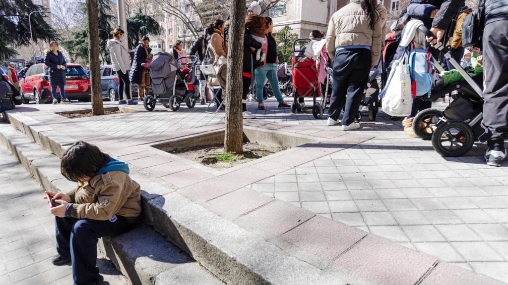 Un grupo de personas espera una cola durante la entrega de ropa de abrigo y zapatos nuevos a niños vulnerables.