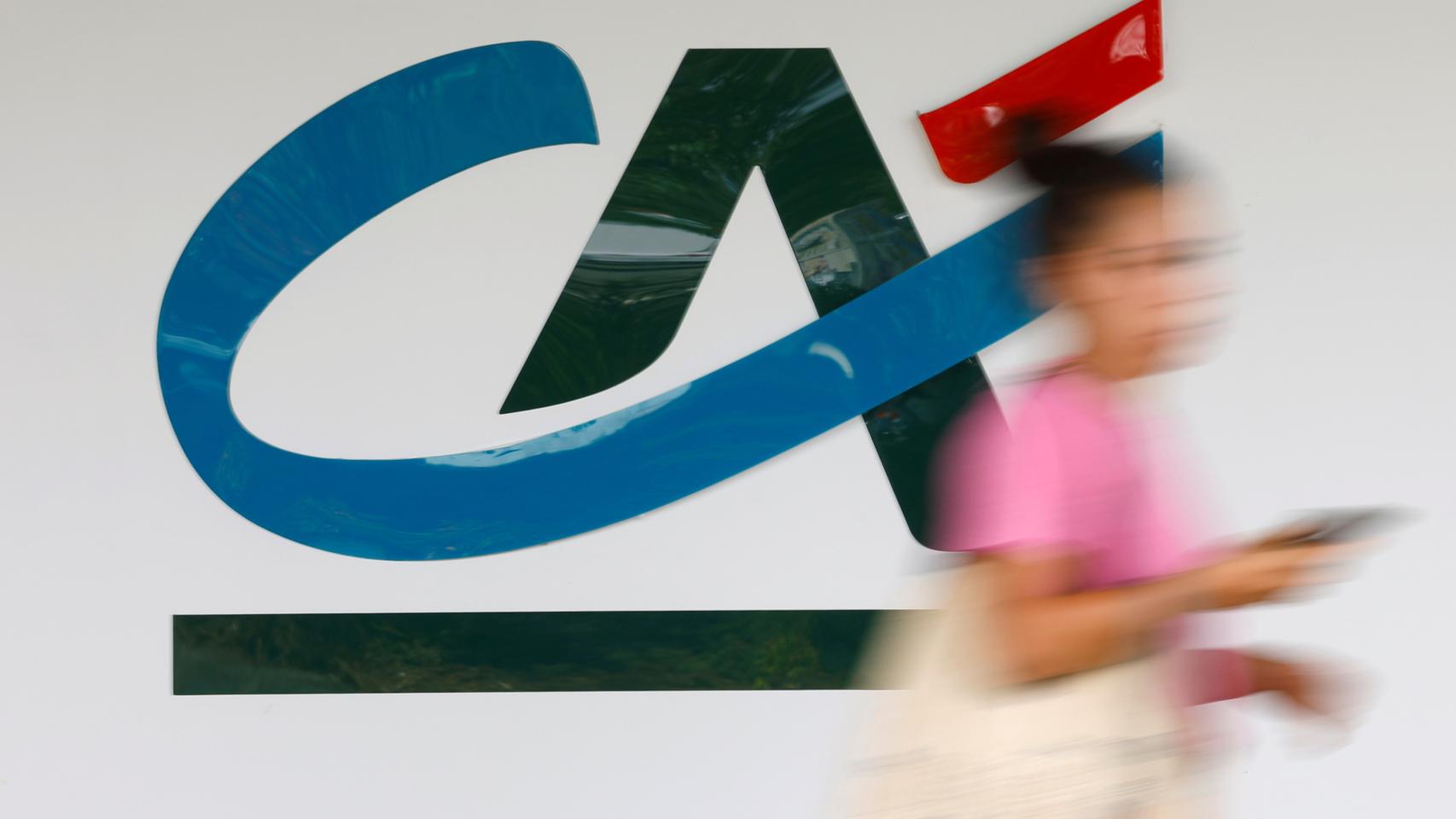 Una mujer pasa por delante de una oficina de Crédit Agricole.