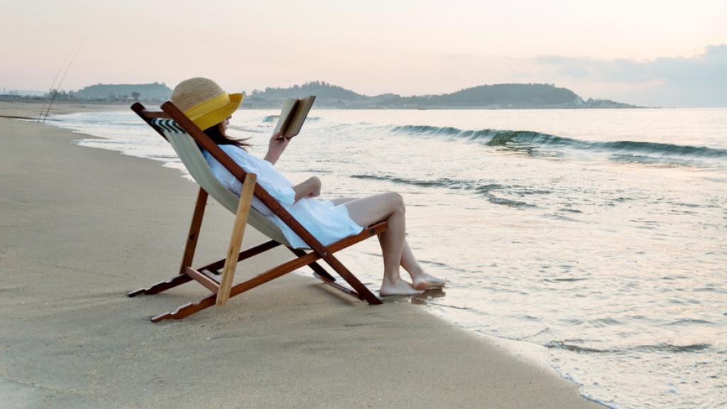 Una mujer disfrutando de la lectura en la playa. Foto: iStock.
