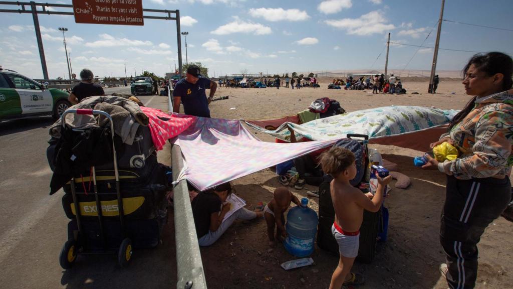 Una familia espera ante la frontera de Chile con Perú, en la ciudad chilena de Arica, este miércoles.