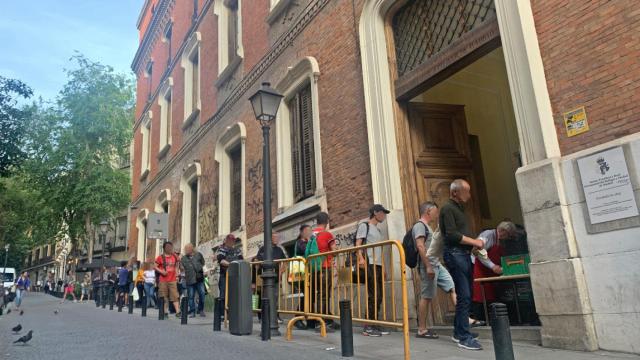Varias personas hacen cola para recibir la cena en la Real Hermandad del Refugio y Piedad, en Madrid.