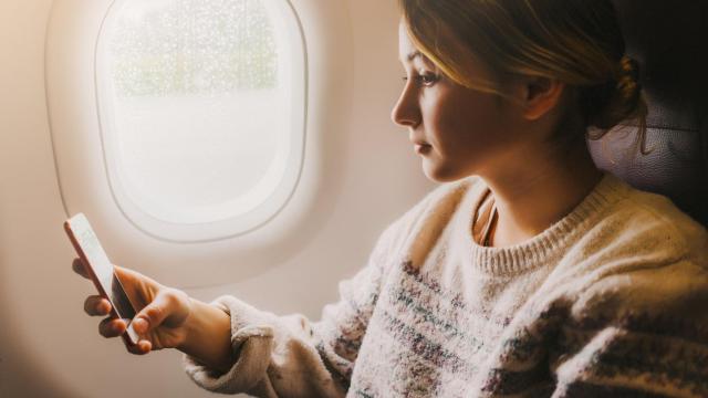 Una persona usando el móvil en un avión.