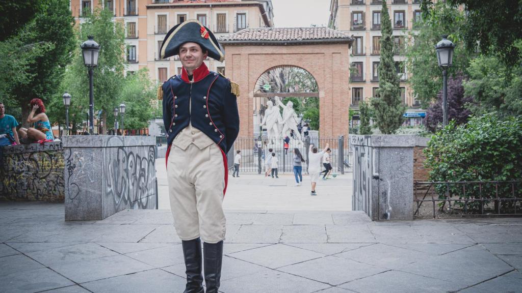 Carlos, caracterizado como el heroico capitán, posa con el conjunto escultural de Daoiz y Velarde de fondo.