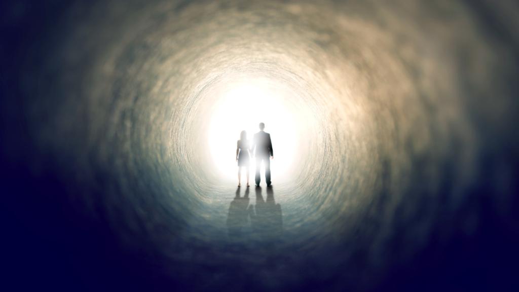 Dos personas caminan hacia la luz del final del túnel.