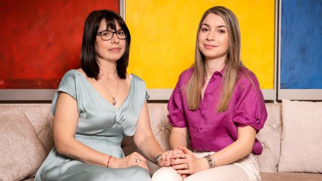 Mariana y Ana María posan delante de los colores de la bandera rumana.