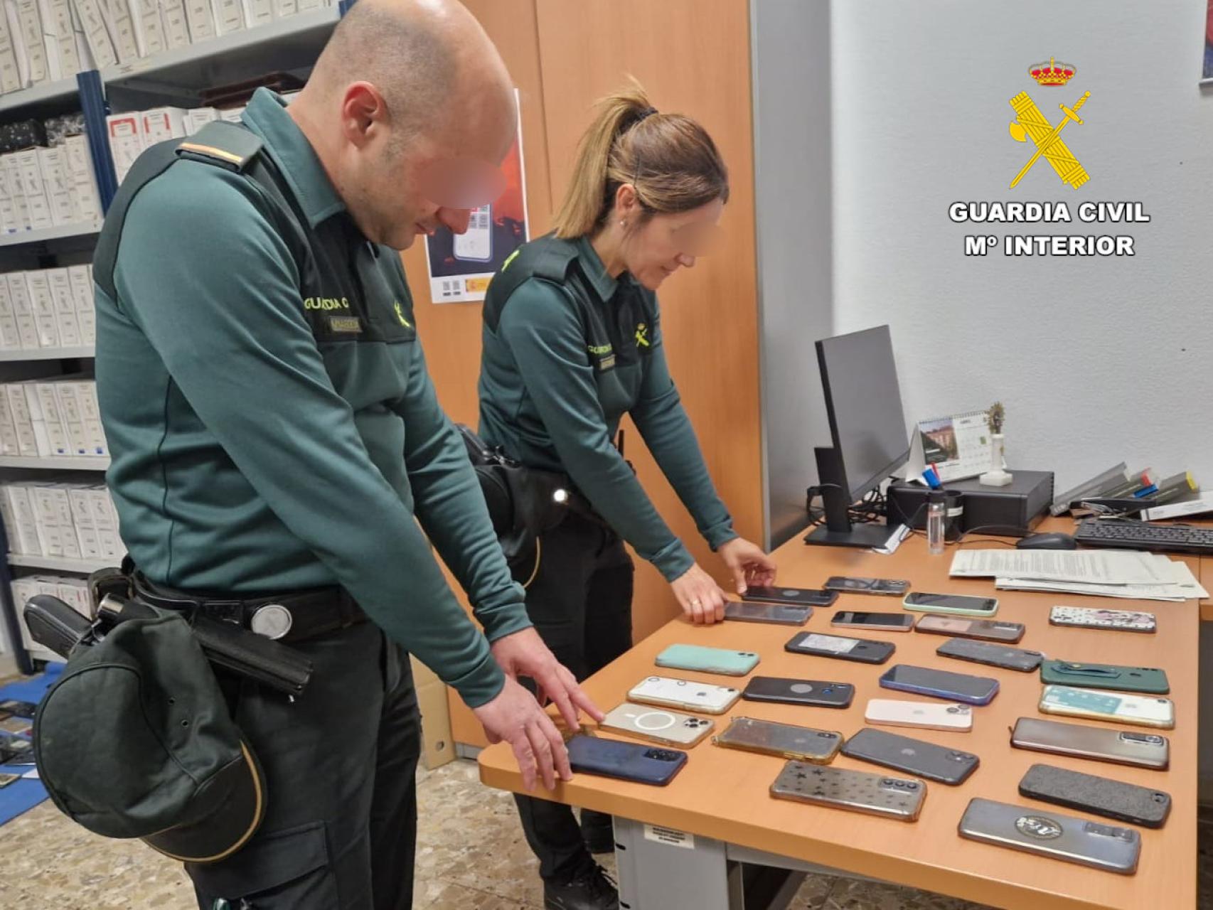 Dos agentes de la Guardia Civil junto a varios teléfonos móviles robados durante el Viñarock.