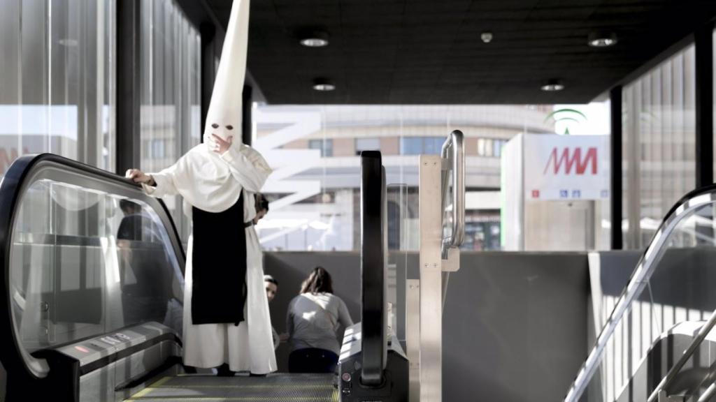 Un nazareno de Semana Santa saliendo de una de las estaciones del Metro de Málaga.