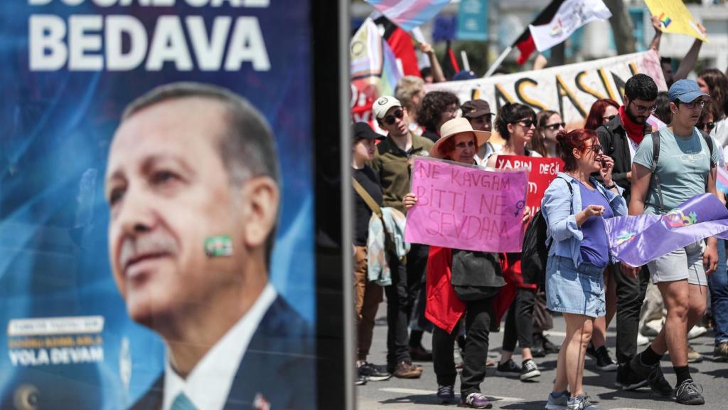 La gente sostiene pancartas cerca de una imagen del presidente turco Recep Tayyip Erdogan, durante un mitin de celebración del Primero de Mayo