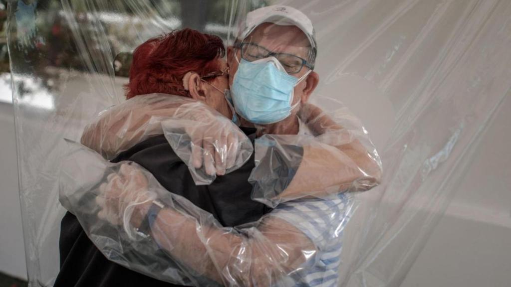Dos personas se dan un 'abrazo Covid-19' en la residencia de ancianos Ballesol Valterna en València.