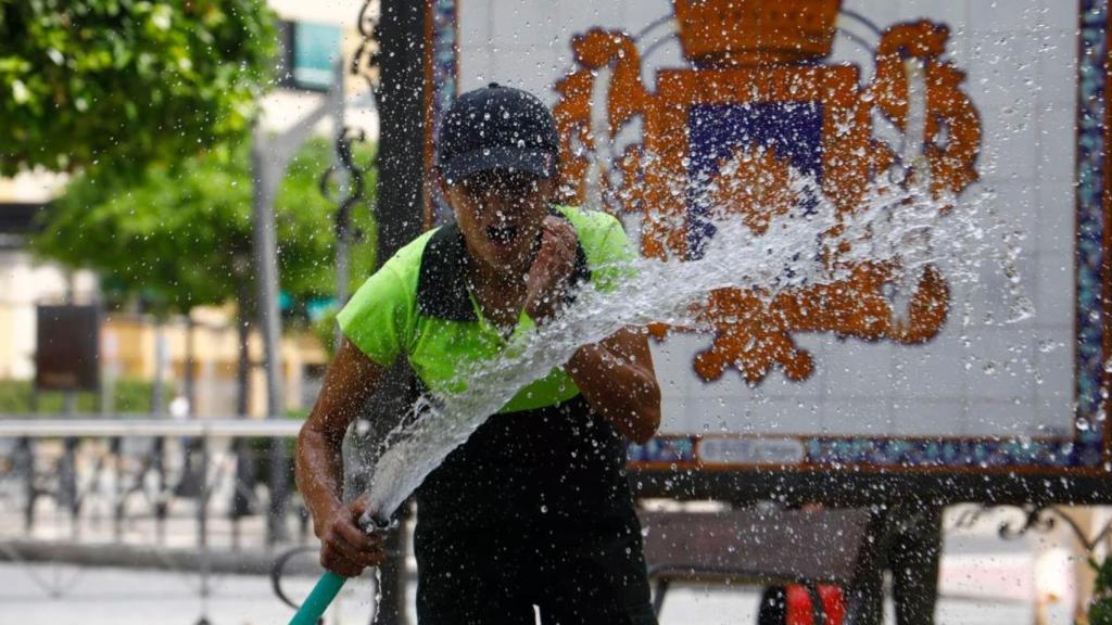 Una operaria se refresca en pleno calor de finales de abril.