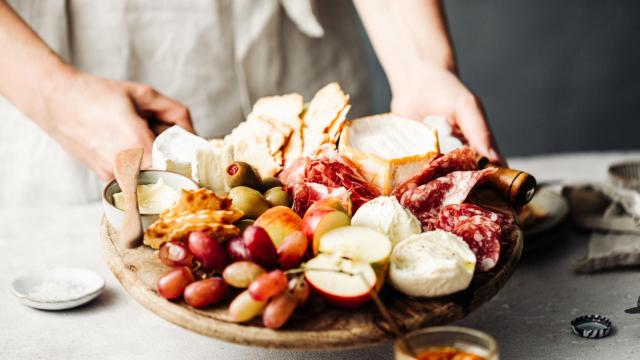 Mujer sirviendo un plato de aperitivo en la mesa. Foto: iStock.
