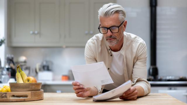 Un hombre revisa una notificación de la Agencia Tributaria en su domicilio.