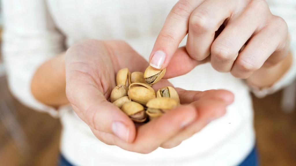 Mujer comiendo pistachos.