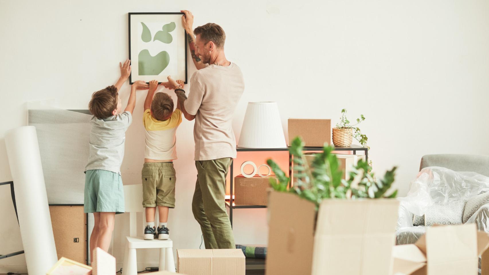 Una familia colgando un cuadro juntos.