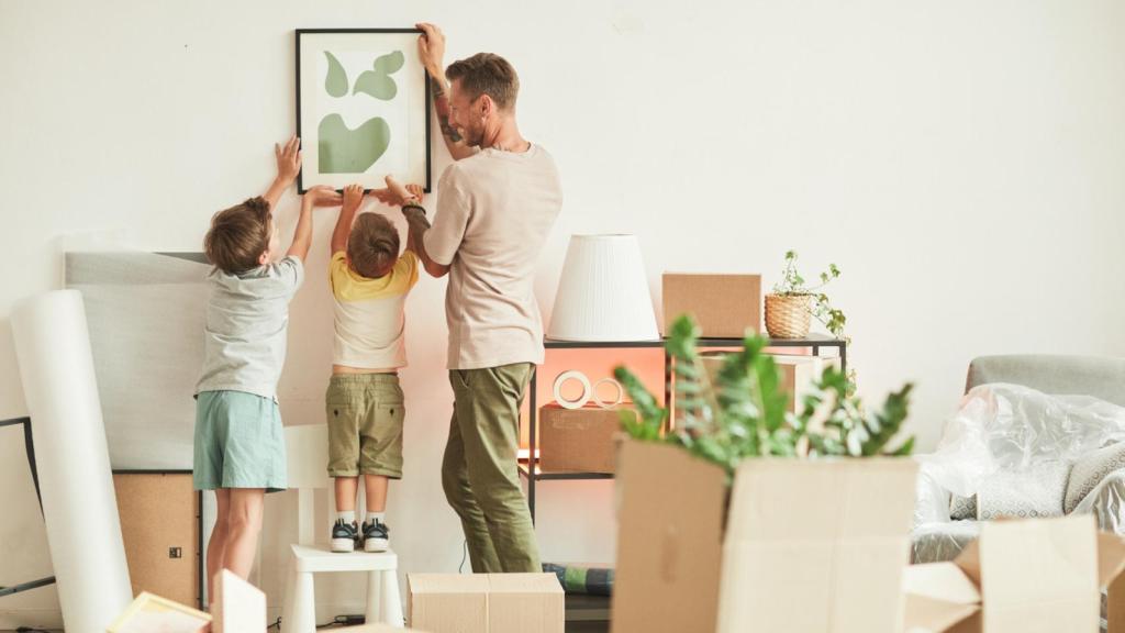 Una familia colgando un cuadro juntos.